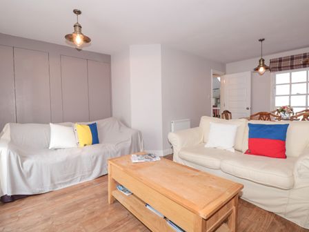 A living room with two sofas a wooden coffee table and hanging ceiling lights at Upper 3 in Dartmouth