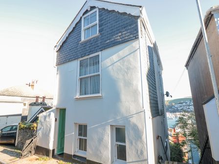A narrow white house with a green door and multiple windows near a harbor at 19 Above Town in Dartmouth