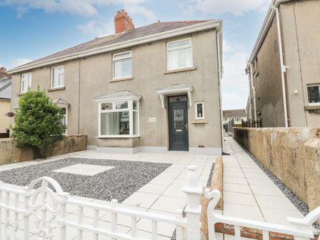 A semi detached house with a tiled front yard and a white metal gate at Larkhill in Tenby
