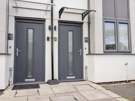 Two grey front doors with glass panels under canopies and adjacent windows at 16 Ocean Heights in Newquay