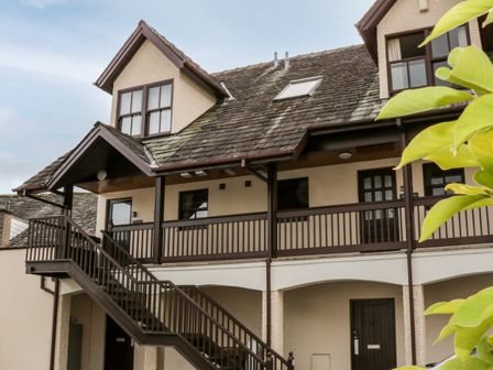 A two story building with a staircase leading to a balcony and several doors with windows at Derwent Haven in Keswick