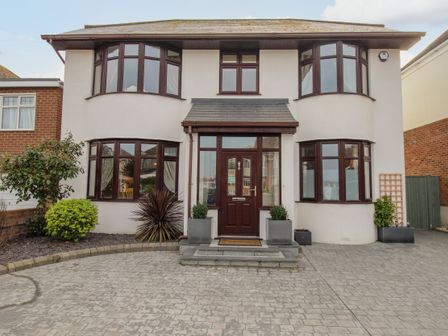 A two story detached house with bay windows and a central front door with plants on each side at Family House in Weymouth