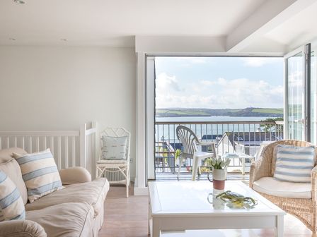 A living room with sofa, armchairs, coffee table, and balcony overlooking the water at Slipway 19 in Rock