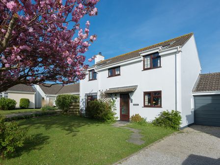A two story white house with a brown door and windows next to a garage and a flowering tree in the garden at Hazelhurst in Rock
