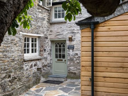 Stone exterior with a green door labeled Porthilly Greys and wooden siding at Porthilly Greys in Rock