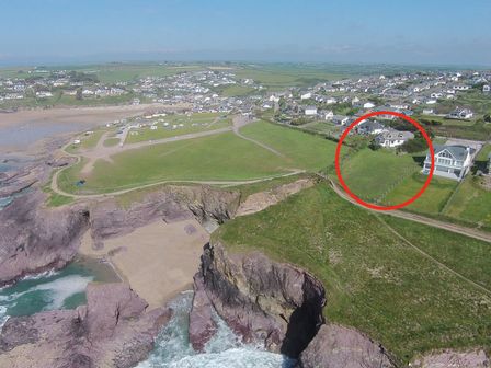 A coastal area with cliffs green fields houses and a beach with a section circled in red at Gullsway Sandpiper in Polzeath
