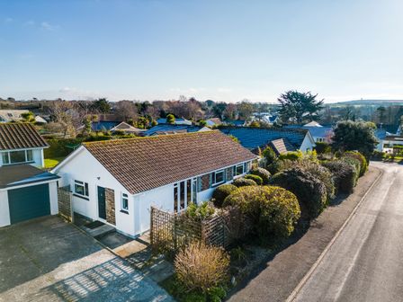 A single-story house with a tiled roof and attached garage surrounded by bushes along a street at Little Sailing in Rock