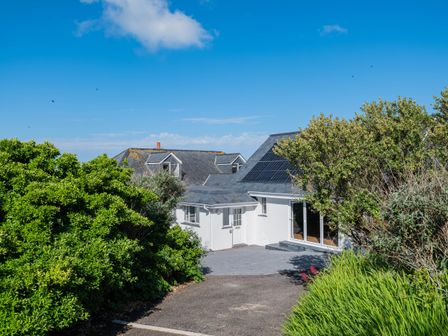 A house with solar panels on the roof surrounded by bushes and a driveway at Treverden in Polzeath
