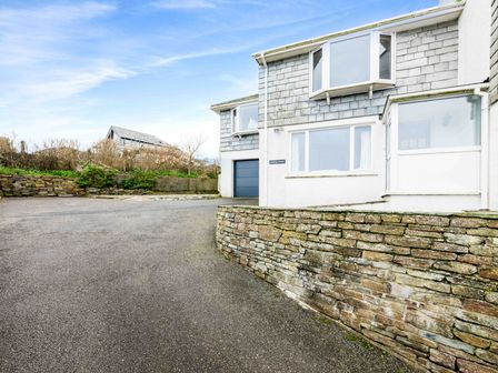 An exterior view of a house with stone wall and driveway at Shilling Stones in Port Isaac