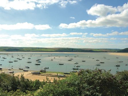 A coastal view with boats anchored in the water and green fields in the background at Carn Du 1 in Rock