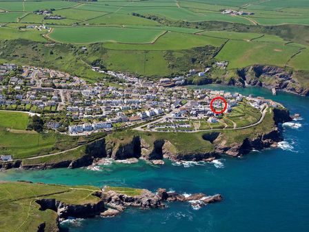 An aerial view of a coastal town with houses green fields and cliffs by the sea at The Folly in Port Isaac
