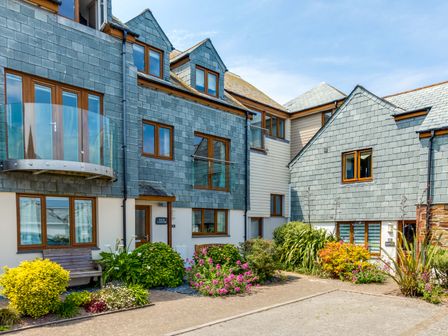 The exterior of a residential building with blue slate cladding wooden framed windows a glass balcony and garden in front at Rock Lobster in Port Isaac