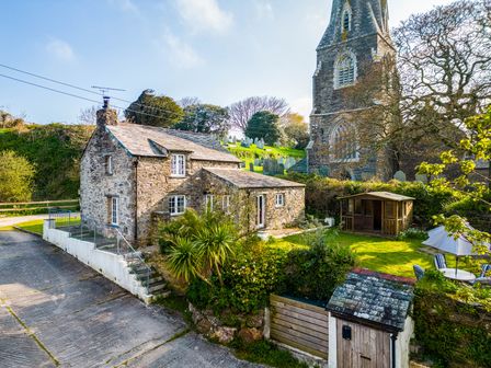 A stone cottage with a small garden and shed next to a church and graveyard at Dingles Cottage in Rock