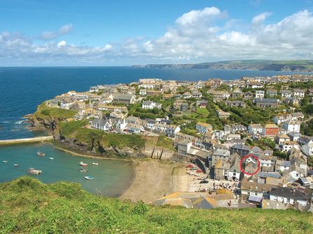 A coastal village with houses along a bay and boats in the water at Cloam Cottage in Port Isaac