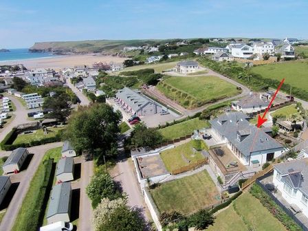 An aerial view of houses near a beach and green fields at Pendaveli in Polzeath