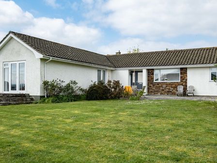 A single-story house with white walls and a tiled roof and a grassy lawn in front at Corriana in Rock