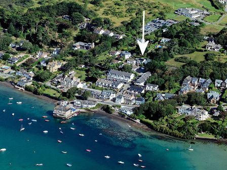 An aerial view of a coastal village with houses trees parked cars boats in water and an arrow pointing to a specific building at Drifters in Rock