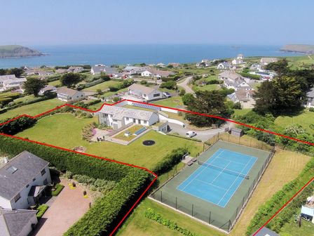A house with a tennis court and surrounding garden near the coast at Downalong in Daymer Bay