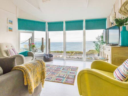 A living room with armchairs a television and a window view of the sea at The View in Port Isaac
