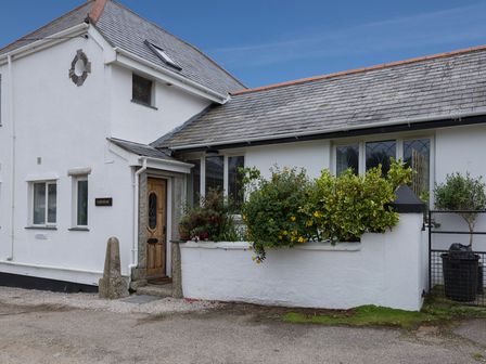 The exterior of a white house with a wooden door and small garden at Fairholme in Port Isaac