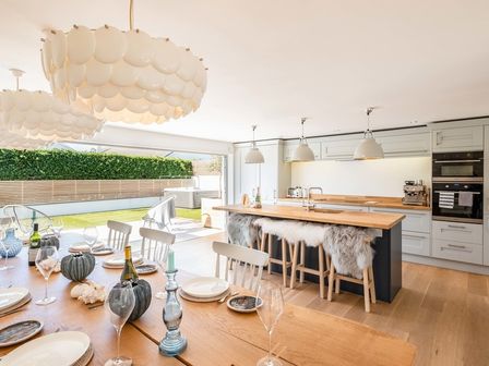 A kitchen and dining area with wooden table set for dining and kitchen island with stools at Seastar in Rock
