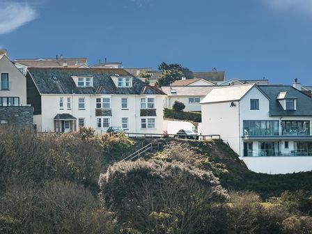A cluster of houses on a hillside surrounded by trees at Pinewood 14 in Polzeath
