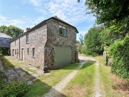 A cottage with stone wall and green door at Orchard Cottage in Polzeath