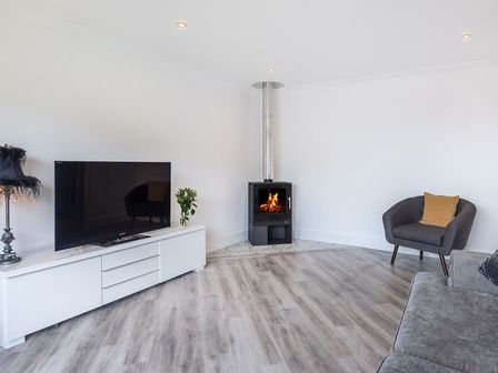 A living room with a television on a cabinet a wood stove and seating at Greenaway 4 Rockhaven Gardens Rock