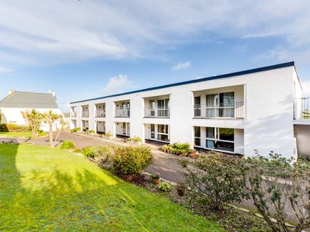 An exterior view of a white two-story building with balconies and a garden area at Westward 8 in Polzeath