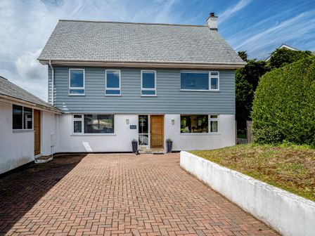 A paved driveway leading to a two-story house with blue siding on the upper floor and white walls on the lower floor at Flaad House in Rock