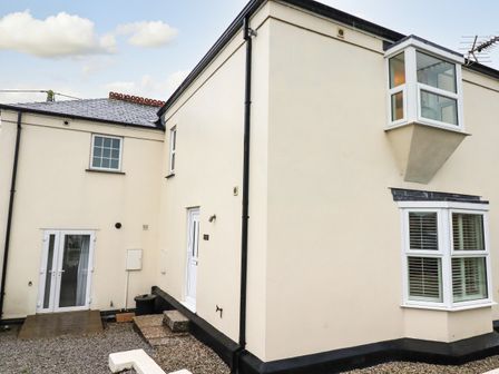 Exterior view of a cream colored house with multiple windows and two doors at 1 Old Talbot Cottages in Lostwithiel