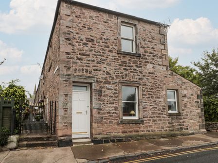 A stone house with a white door and three windows on a street at Islestone 1 Temperance Terrace in Berwick-Upon-Tweed