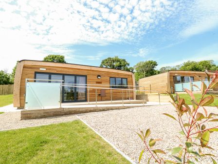 Two wooden cabins with glass railings and gravel paths surrounded by grass and trees at Syrah in Seaview