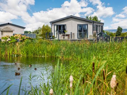 A house with a deck and outdoor furniture near a pond with ducks at Number 8 Lakes View in Brean