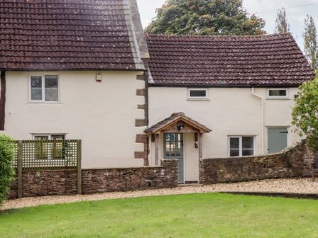 A stone cottage with tiled roof a small porch and a green door at 1 White House Cottages Bromsash near Lea
