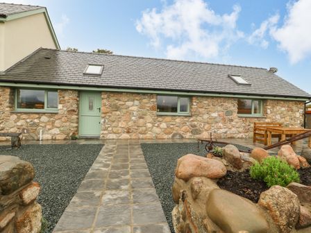 A stone house with green windows and door a paved pathway and gravel garden at Y Felin The Granary in Caernarfon