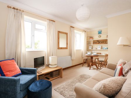 A living room with a beige sofa blue armchair small wooden table and shelves at 16 Norfolk Heights in Docking