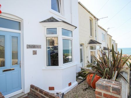 Exterior view of a row of houses with bay windows a blue door and a plant in a pot at The Shambles in Fortuneswell