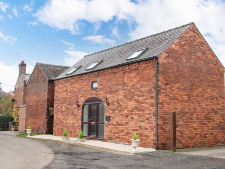 A red brick building with skylights and a wooden door with glass panels at The Little Beehive in Abberley