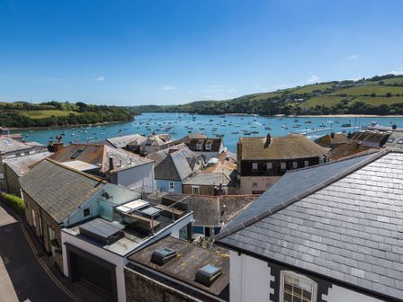 View of rooftops and boats on water with green hills in the background at 2 Church Hill House in Salcombe
