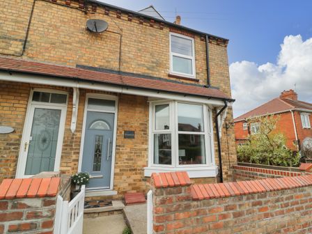 The exterior of a brick house with a blue door a bay window and a small front garden at Westfield in Flamborough East Riding