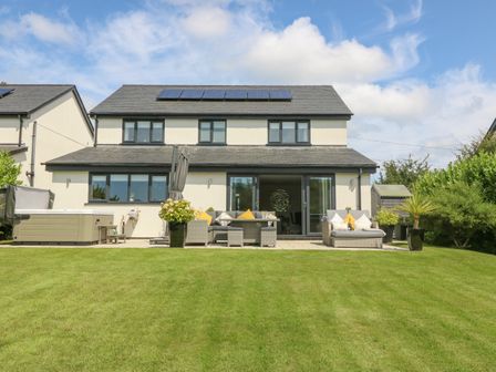 A backyard with lawn seating area and hot tub at Berllan in Llanbedrgoch near Benllech