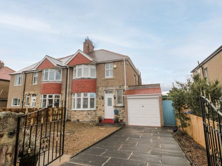 A semi detached house with a driveway garage and gated front yard at Shileen in Seahouses