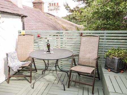 An outdoor seating area with two chairs and a round metal table with a bottle and glasses at 7 Watkin Street in Conwy