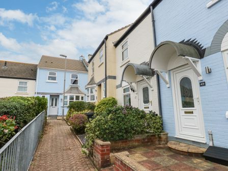 A row of houses with white and blue walls and small gardens along a brick pathway at Little Tern Brewers Quay Harbour