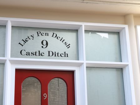 A red door with glass panels and the number 9 above it at Llety Pen Deitsh 2 in Caernarfon