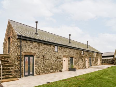 A stone barn conversion with multiple doors and windows and outdoor steps at Sgubor in Llangefni