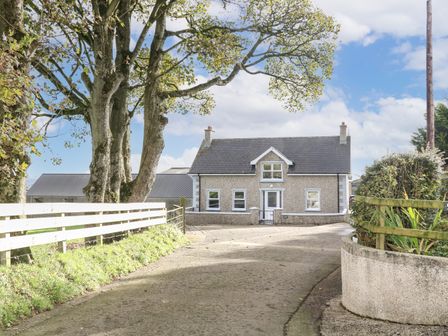 A driveway leading to a detached house with white framed windows and a slate roof at Granny's in Bushmills County Antrim
