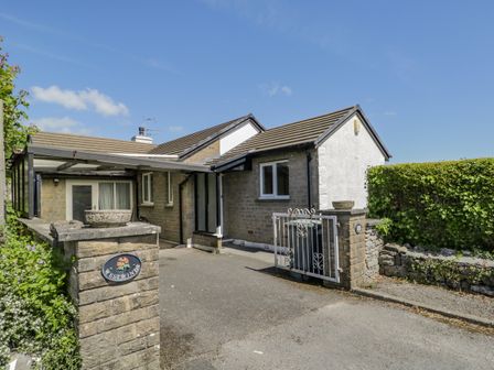 The exterior front view of a single story house with a driveway and a gate at Westwinds in Grange-Over-Sands