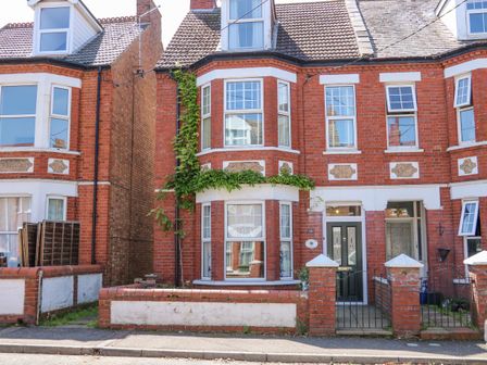 A red brick terraced house with white window frames and a small front garden at Apple Tree House in Hunstanton